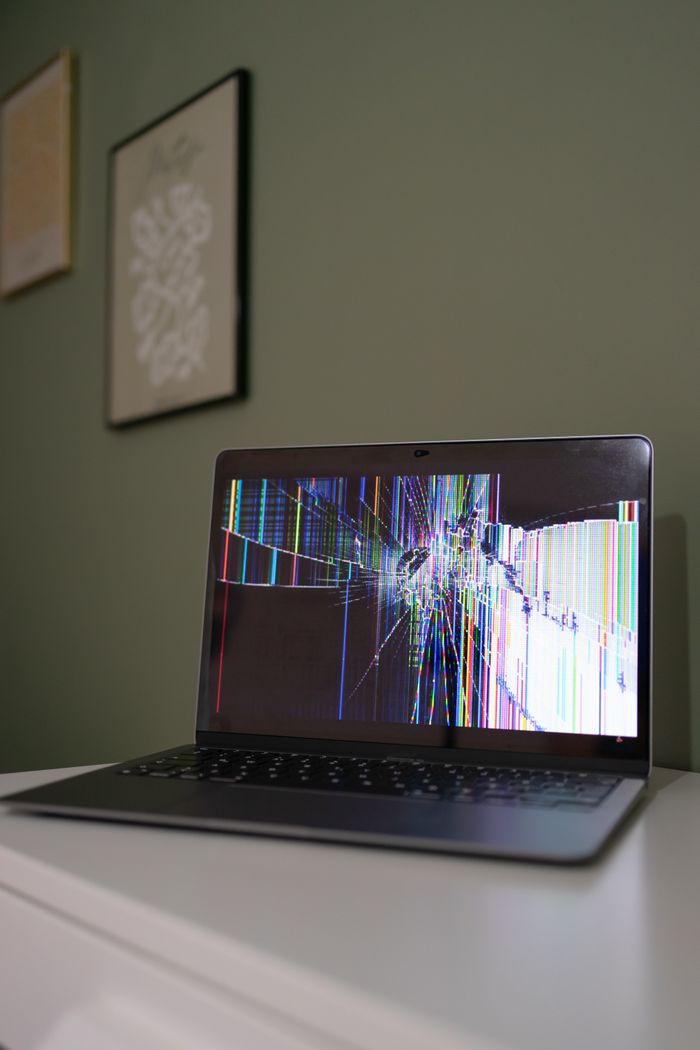 Mastering the First Impression: Your intriguing post title goes here A laptop with a cracked and malfunctioning screen displayed on a desk indoors.