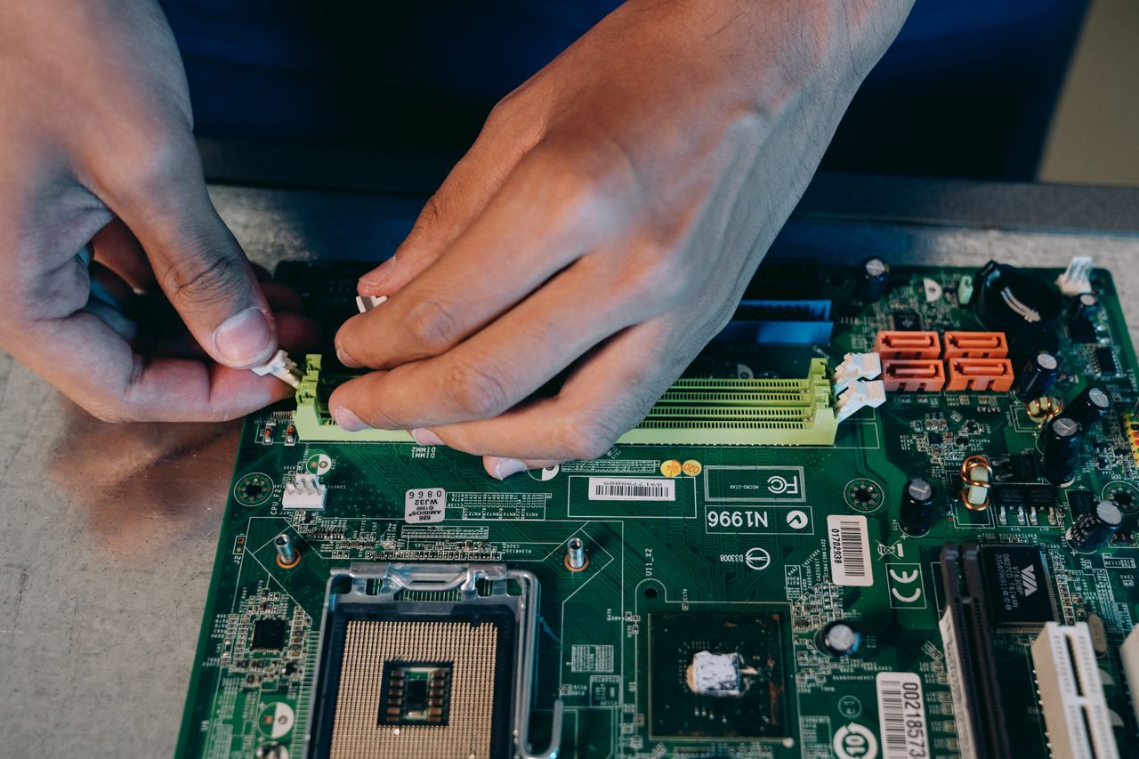 Crafting Captivating Headlines: Your awesome post title goes here Hands carefully assembling a computer motherboard, showcasing technical craftsmanship in electronics.
